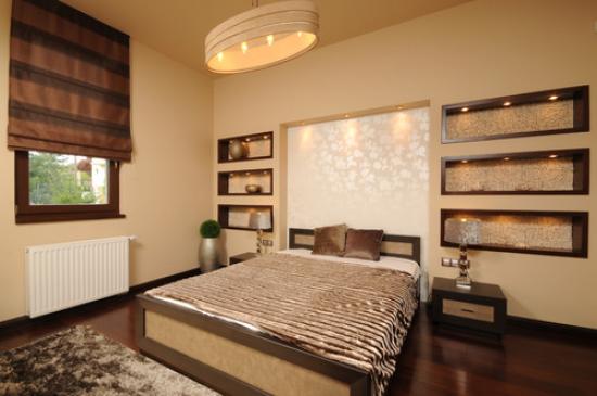 Bellissime nicchie in cartongesso con illuminazione decorativa sulla parete in testa al letto in camera da letto