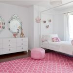 Il tappeto e il pouf rosa acceso risaltano sulle pareti bianche.
