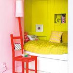 Un piccolo letto in una nicchia con cassetti e separato per colore dal resto della stanza