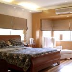 Letto con testiera curva in una stanza d'angolo con ampie finestre