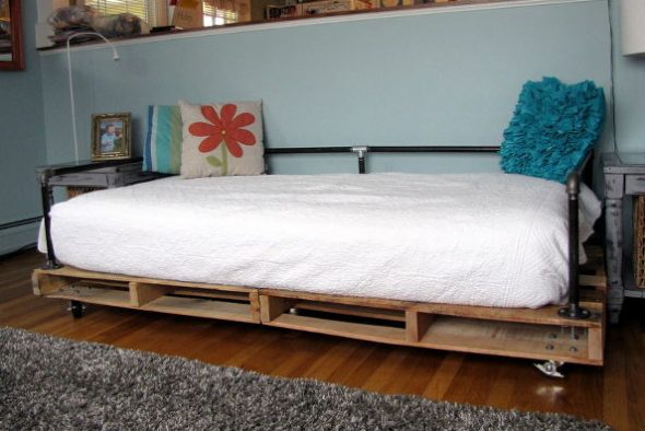 Letto realizzato con pallet di legno e tubi metallici