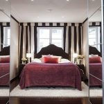 Letto lussuoso vicino alla finestra in una stanza con armadi a specchio