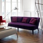 Divano viola con cuscini bordeaux sulle gambe
