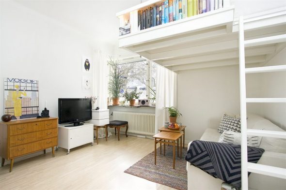 Monolocale con un letto al piano superiore per dormire e una zona soggiorno al piano inferiore
