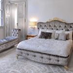 Bellissimo letto con testiera morbida e lungo pouf morbido in camera da letto