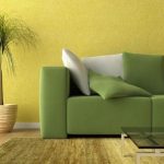 Divano verde contro muro giallo