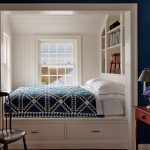 Letto in una nicchia vicino alla finestra con mensola incorporata per i libri