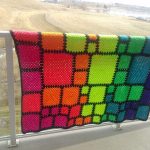 Una coperta insolita fatta di quadrati multicolori di diverse dimensioni con un motivo arcobaleno