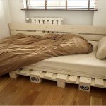Letto singolo realizzato con pallet nell'angolo della stanza