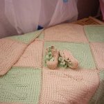Delicata coperta verde e rosa, lavorata a maglia con i ferri