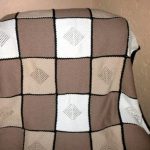 Coperta nei colori crema e pastello, lavorata a maglia con i ferri