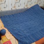 Una grande coperta-copriletto lavorata a maglia blu è adatta per un letto o un divano