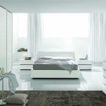 Moderna camera da letto bianca come la neve con un letto vicino a una finestra panoramica