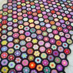 Insolita coperta floreale con fiori lavorati a maglia multicolori