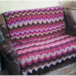 Una coperta per divano realizzata con filati di scarto, lavorata a maglia con strisce a zigzag multicolori
