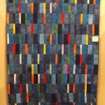 Una coperta-copriletto realizzata con strisce di denim e inserti luminosi