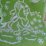Coperta verde e bianca con un coniglietto in un prato