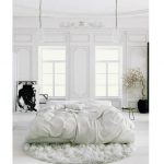 Camera da letto bianca minimalista con un materasso sul pavimento per dormire e rilassarsi