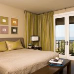 In una camera da letto con carta da parati color sabbia vengono utilizzate tende giallo-verde pallido