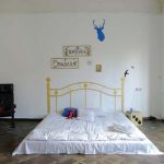Materasso sul pavimento con foglie dipinte per la decorazione in una stanza arredata in stile minimalista