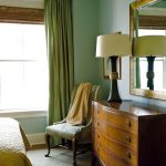La camera da letto in stile eclettico presenta tende e pareti verdi