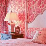 Camera da letto con carta da parati rosa e tende completate da un motivo floreale