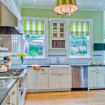 La cucina spaziosa e luminosa è caratterizzata da una parete decorativa verde chiaro e da tende verdi con strisce bianche.