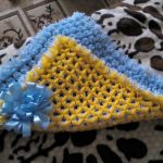 Insolita coperta gialla e blu fatta di pompon