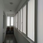 Tende bianche alle finestre di uno stretto balcone