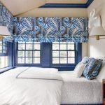 Camera da letto con numerose finestre coperte da tende alla romana