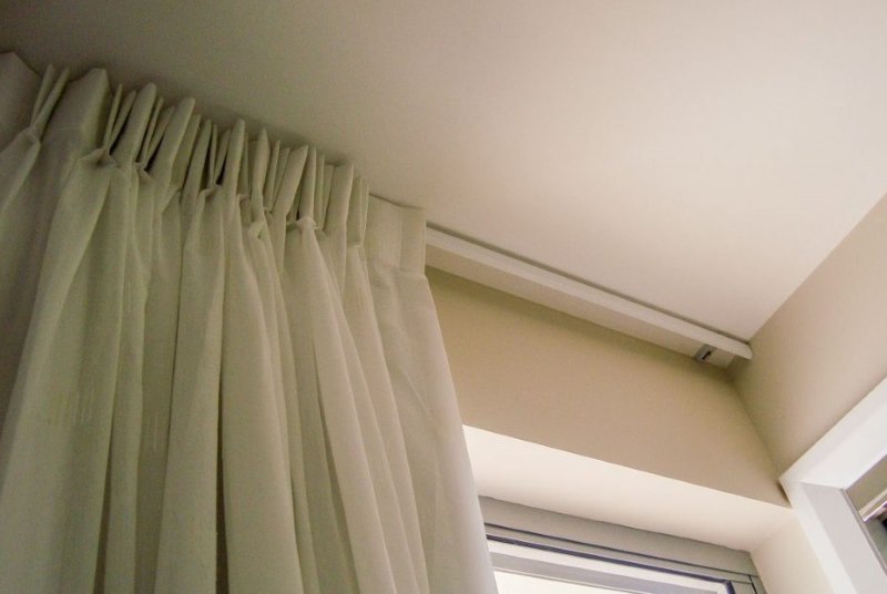 Fissaggio di una tenda bianca alla cornice di una mensola