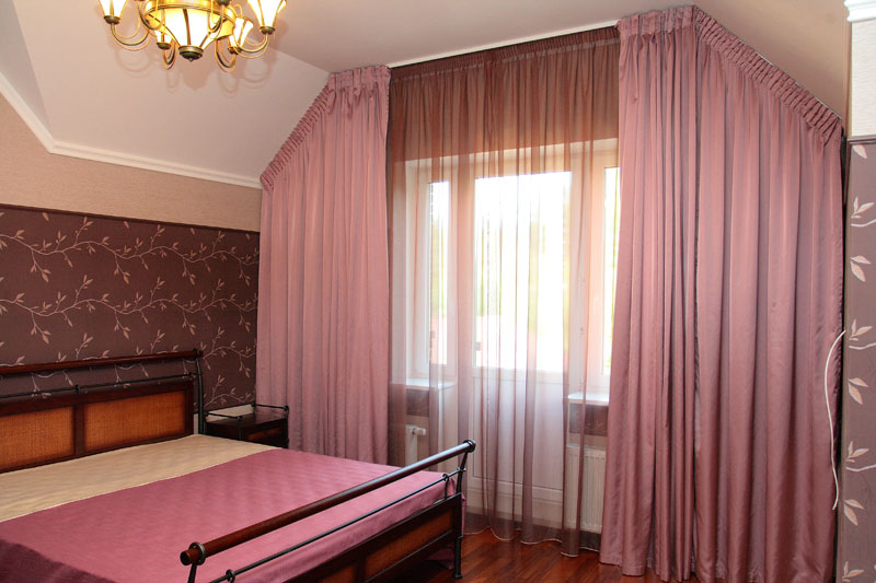 Decorare una finestra con le tende in una camera da letto mansardata