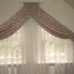 Due finestre simmetriche con inserti triangolari in tulle e lambrequin