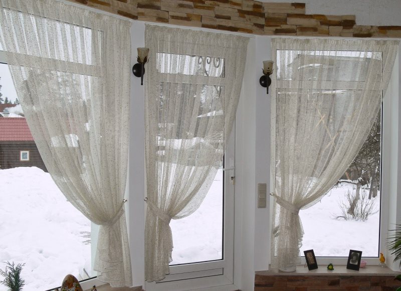 Tende di tulle ingrigite alle finestre di una casa di campagna