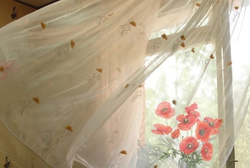 Una tenda leggera svolazza nel vento da una finestra aperta