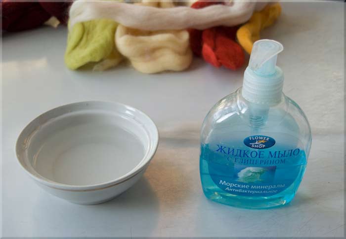 Una bottiglia di sapone liquido e acqua in una tazza