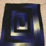 Piccola coperta lavorata a maglia a spirale nei toni scuri