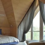Tende chic per una finestra triangolare in una camera da letto in mansarda