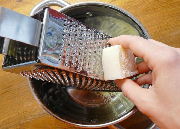 Macinare il sapone da bucato su una grattugia di metallo