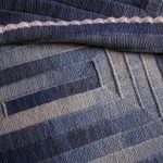 Coperta lavorata a maglia nei toni del blu con ferri da maglia
