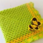 Coperta gialla-verde lavorata a maglia con una farfalla
