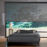 Letto grigio davanti a una grande finestra