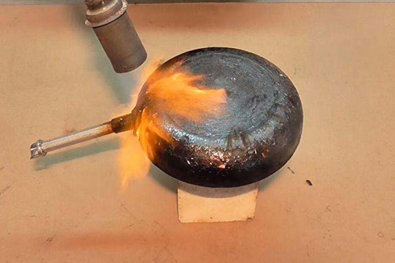 pulizia dei depositi di carbonio da una padella con un cannello a gas