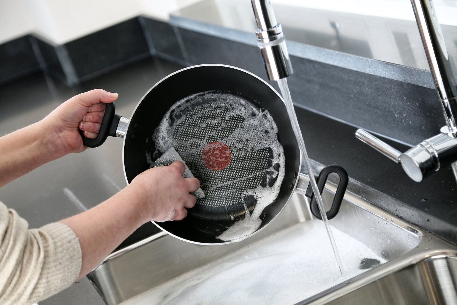 Padella in teflon sotto il rubinetto